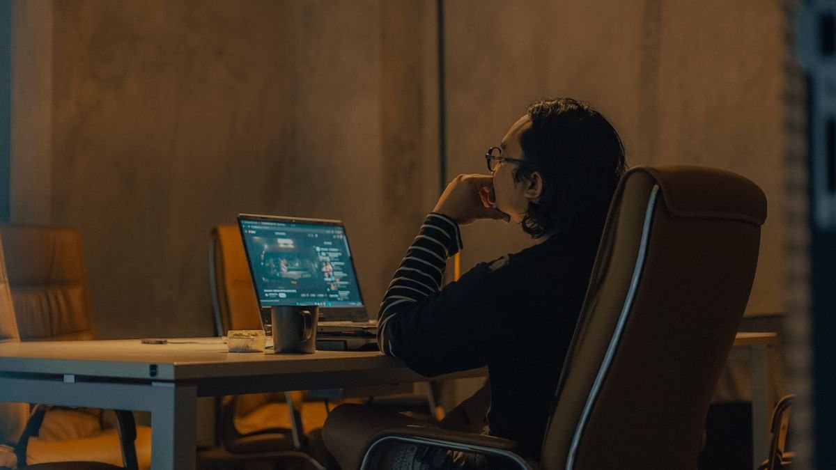 Man at a desk working on his laptop in the evening