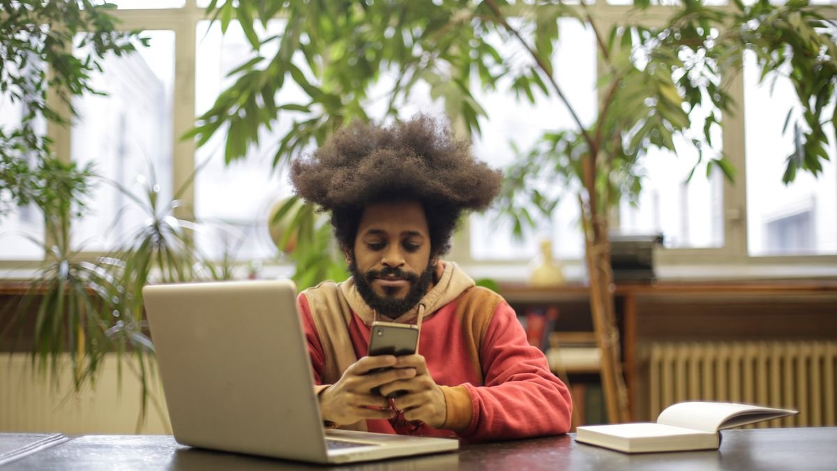 Student using a laptop and a smartphone in a library